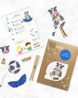 Cow-themed peg doll kit with instructions and materials on a white background