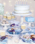 Frozen 2 Elsa Anna birthday party supplies with character plates, cups, napkins, white birthday cake, cupcakes and winter wonderland decorations for Disney princess Frozen party