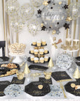 Decorated party table with New Year's Eve theme featuring balloons, plates, and dessert stands.