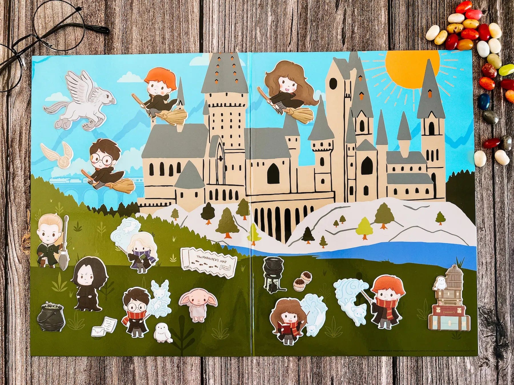 The Hogwarts Puffy Sticker Playset features a colorful cartoon Hogwarts scene with chibi Harry Potter characters, magical creatures, books, cauldrons, candies, and puffy stickers—plus glasses in the corner—for imaginative play.