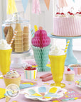 Ice cream sundae birthday party supplies with pastel rainbow plates, yellow sundae glasses, pink cake, waffle cones, tissue paper decorations and sweet treats theme
