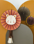 A playful, cozy room features the Party Lion Fan Set—paper lion face and fans—on a mustard wall, paired with a woven lamp and macramé curtain for charming decor.