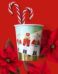 Christmas-themed nutcracker party cup with candy canes and poinsettias on a red background