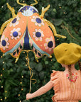 Ladybug balloon party decor floating above child - cute bug themed party supplies for outdoor celebrations