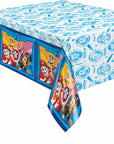 The Paw Patrol Table Cover is a disposable plastic rectangular table cover featuring Chase, Marshall, Skye, and Rubble in vehicles along the sides, with blue badges and symbols decorating the top.