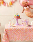 Mermaid scales table cover styled with a mermaid balloon, tiered cake, gift, and pink and purple party decor