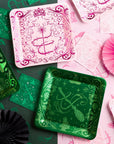 Pink and green Wicked plate pair showing tiara and wand design beside witch hat and broom design