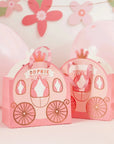 Two Pink Princess Carriage Favour Bags with crown accents and ribbon handles, surrounded by pink balloons and a floral garland. One bag is personalized with “Sophie.”.