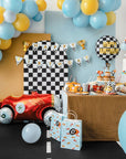 Children's race car themed birthday party setup with balloons, cake, and decorations.