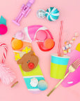 Colorful children's Christmas partyware and candy on a pink background