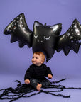 Grabo sparkling bat balloon lifestyle photo with toddler, large black foil bat balloon with metallic stars, Halloween party decoration for kids halloween parties and seasonal celebrations, premium mylar balloon