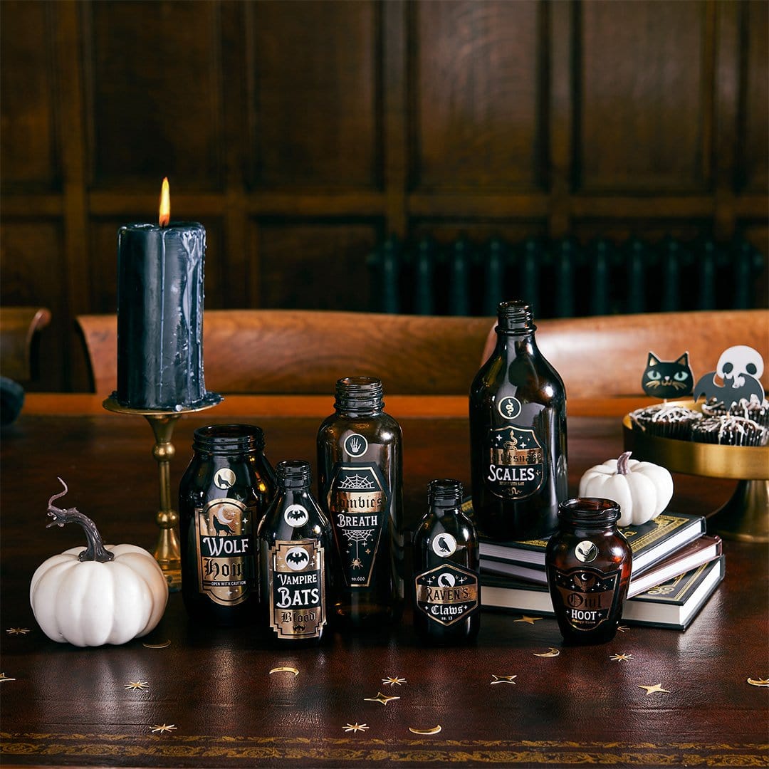 Halloween potion bottles with custom labels display featuring candles and pumpkins, spooky drink bottle stickers for Halloween party table decor, witch potion labels for themed party beverages and Halloween entertaining