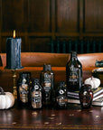 Halloween potion bottles with custom labels display featuring candles and pumpkins, spooky drink bottle stickers for Halloween party table decor, witch potion labels for themed party beverages and Halloween entertaining