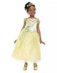 Girl wearing Disney Princess Tiana costume dress with gold tiara and shoes; green and yellow Signature Collection dress for ages 3+ sizes 3T–10