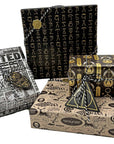 Harry Potter Dark Arts Gift Wrap Set displayed as four wrapped gifts showcasing all wrapping paper designs — black foil spell symbols, Daily Prophet Wanted poster, black and gold Deathly Hallows, and cream Defense Against the Dark Arts — each tied with black and white baker's twine with coordinating foil die-cut gift tags; complete Wizarding World party gift wrapping set for Harry Potter birthdays and themed events