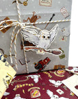 Harry Potter Hogwarts gift wrap with Hedwig owl cutout on gray wrapping paper featuring Platform 9¾ ticket and magical icons, perfect for wizard-themed birthday party supplies