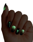 Hand model showing Kiss x Wicked For Good Elphaba Own Your Power press-on nails glowing green in the dark; Elphaba witch hat and ombre nails with glow-in-dark effect; perfect for Wicked theme party