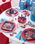 Children's Spider-Man themed birthday party table setting with themed napkins , 9 inch square lunch plates, cups, and cake. Decorated with coordinated spiderman themed party tableware for kids birthday