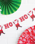 Add festive cheer with the Ho Ho Ho Santa Banner and green, white, and red paper fans featuring cartoon Santa designs, perfect for decorating any space.