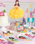 Disney Princess birthday party table setup with hanging pom pom decorations - complete princess themed party supplies tableware and castle centerpiece