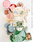 Hogwarts house themed party tablescape with colorful plates featuring house crest cookies, Gryffindor Ravenclaw Slytherin party supplies, white flowers, and magical party decorations for Harry Potter birthday party