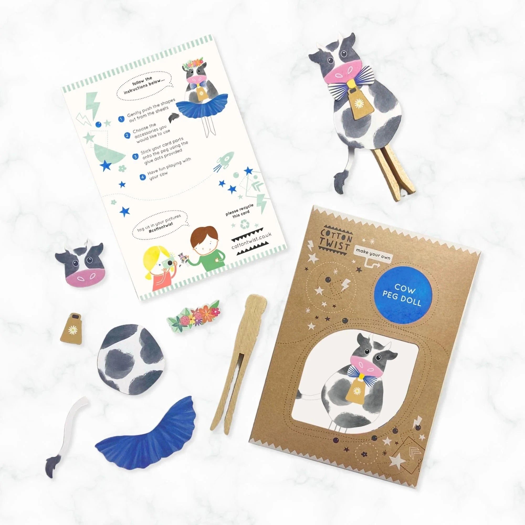 Cow-themed peg doll kit with instructions and materials on a white background