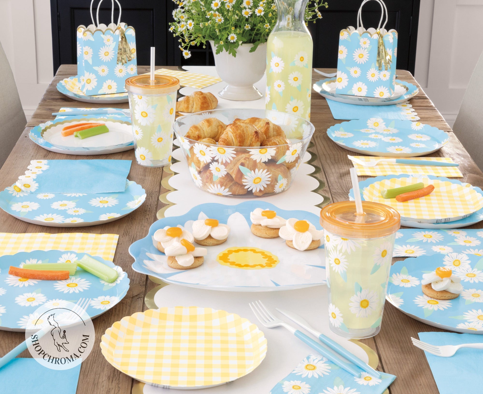 Daisy flower themed kids birthday party supplies set with blue and yellow plates, cups, napkins, gift bags and fresh daisy centrepiece for spring garden party decorations