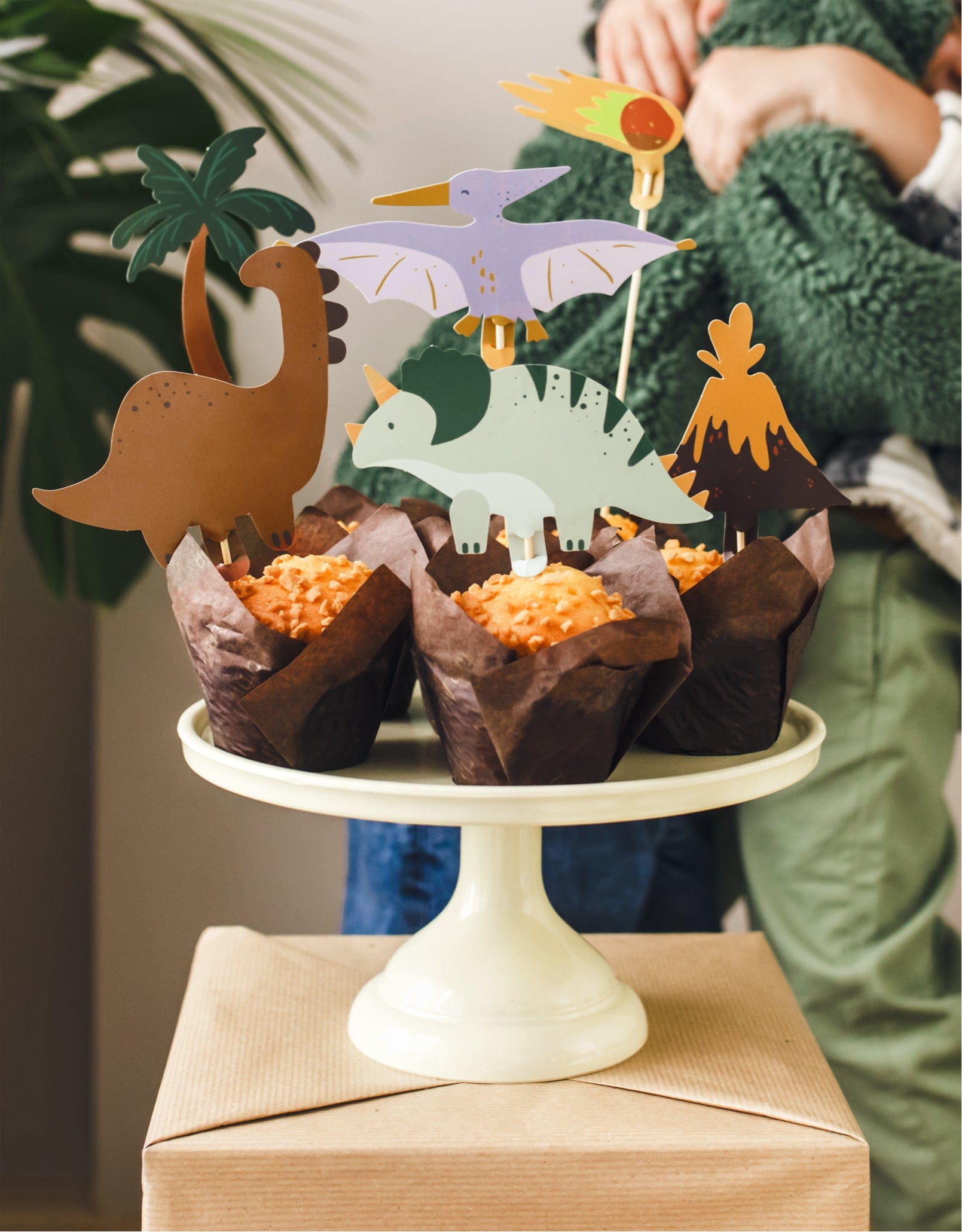 Dinosaur-themed cupcakes on a white cake stand with decorative figures.