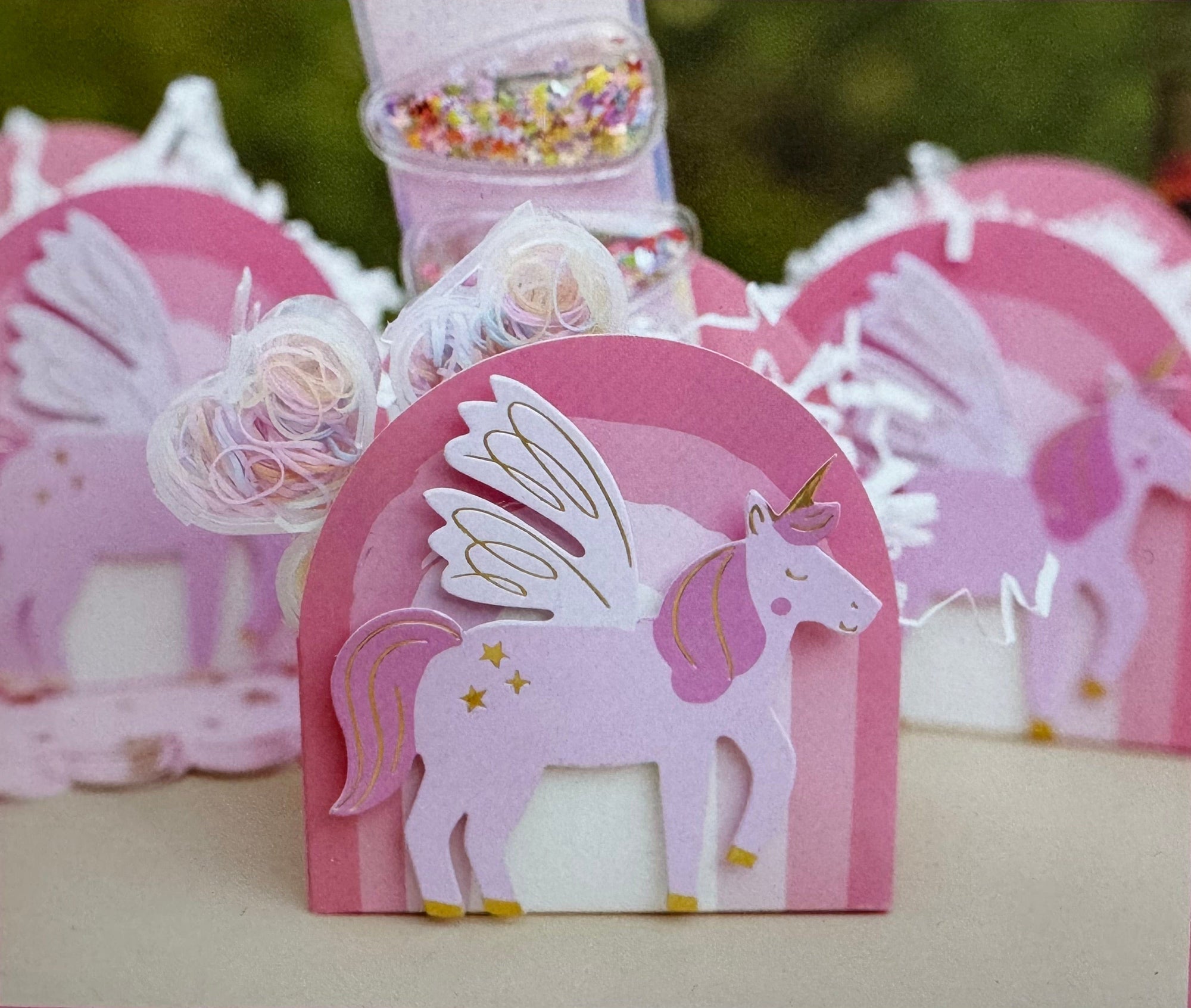Pink unicorn-shaped favour boxes with rainbow decorative elements 