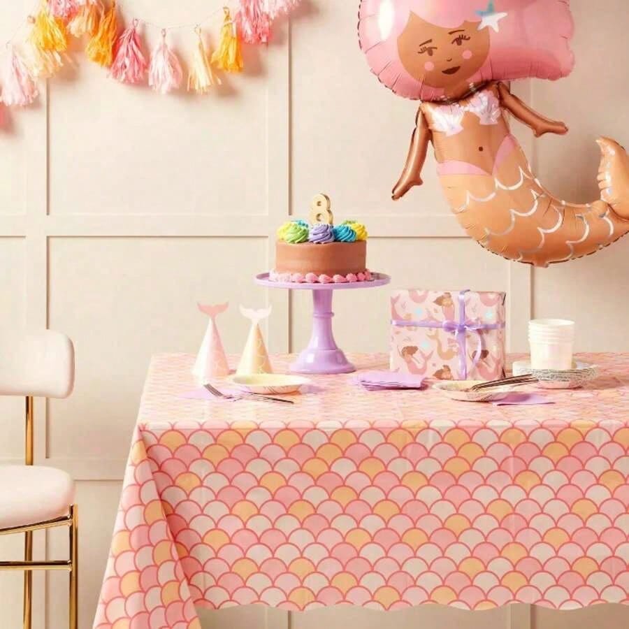 Mermaid scales table cover styled with a mermaid balloon, tiered cake, gift, and pink and purple party decor