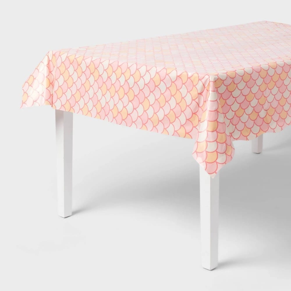 Pink, peach, and cream mermaid scale pattern table cover draped over a rectangular table