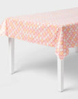 Pink, peach, and cream mermaid scale pattern table cover draped over a rectangular table