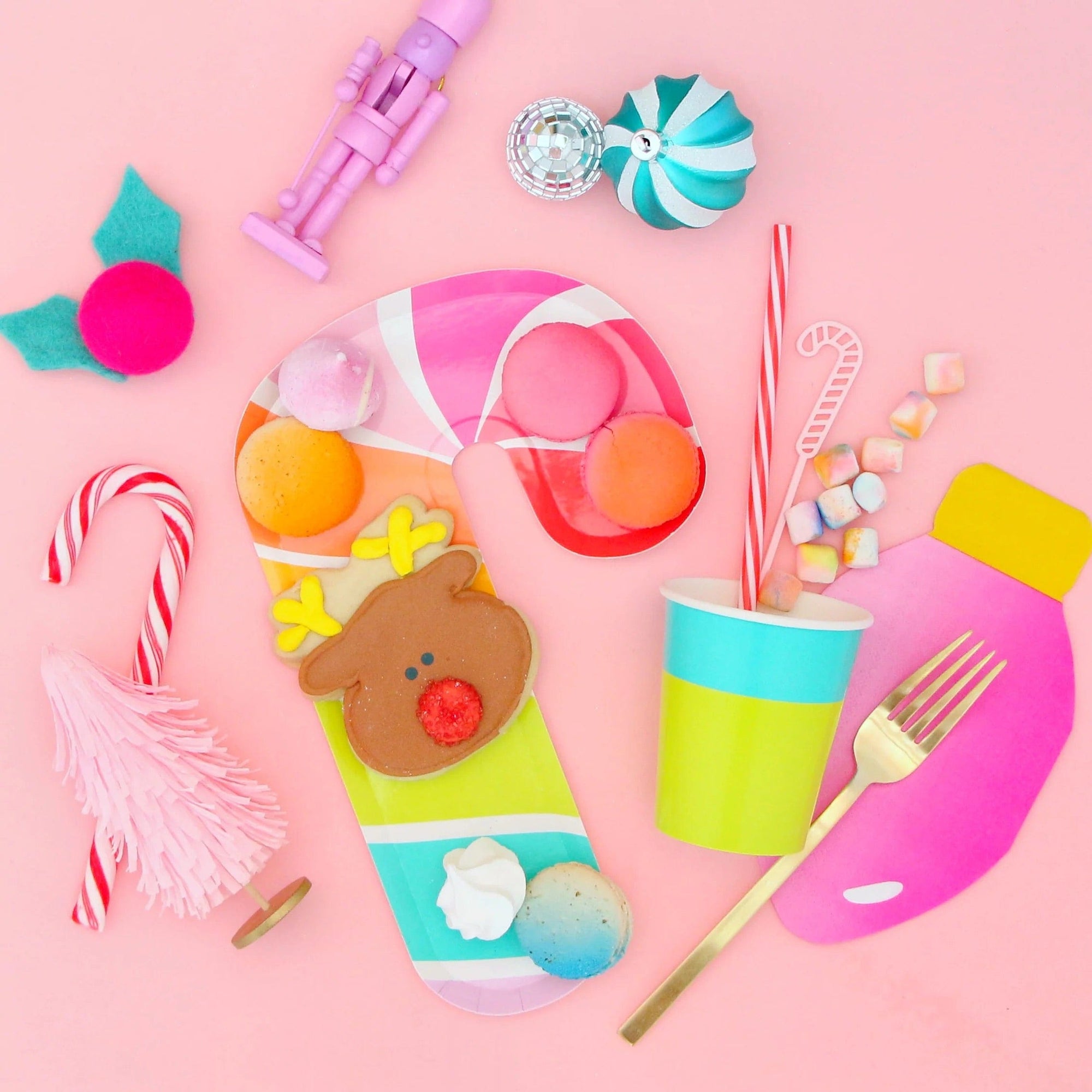 Colorful children's Christmas partyware and candy on a pink background