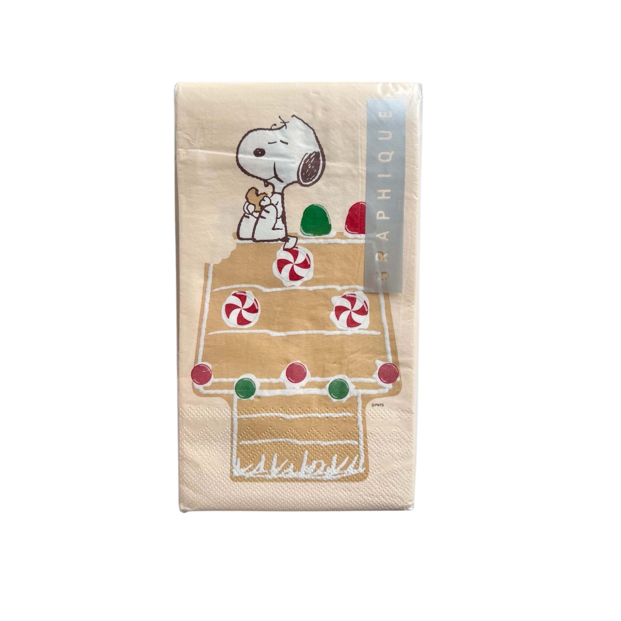 Christmas napkins with a picture of Snoopy from Peanuts, sitting and eating a Christmas cookie on a gingerbread house