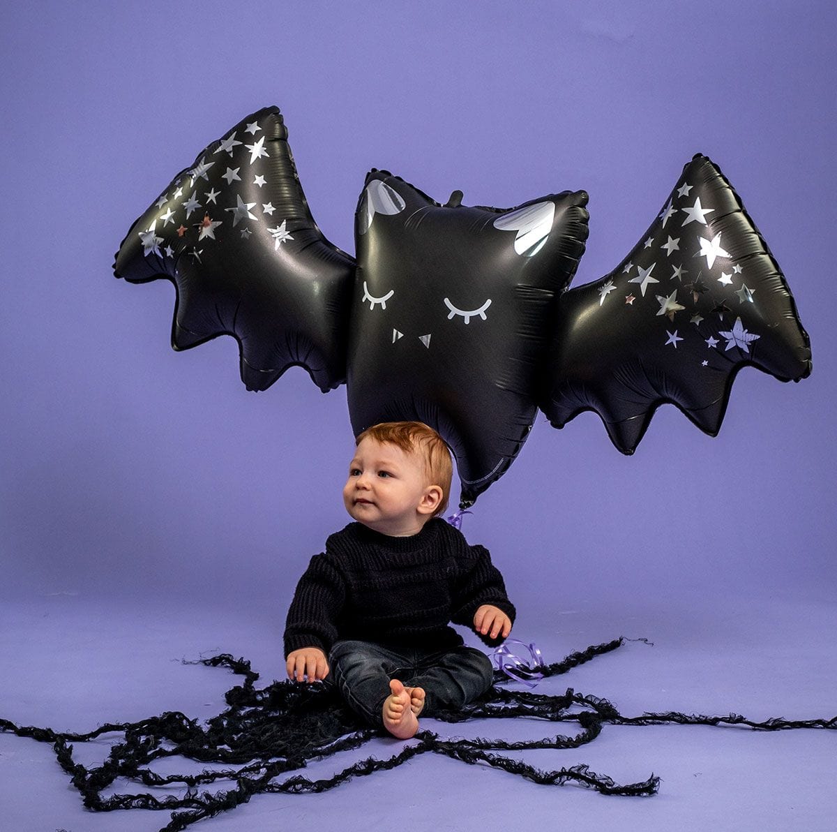 Grabo sparkling bat balloon lifestyle photo with toddler, large black foil bat balloon with metallic stars, Halloween party decoration for kids halloween parties and seasonal celebrations, premium mylar balloon 