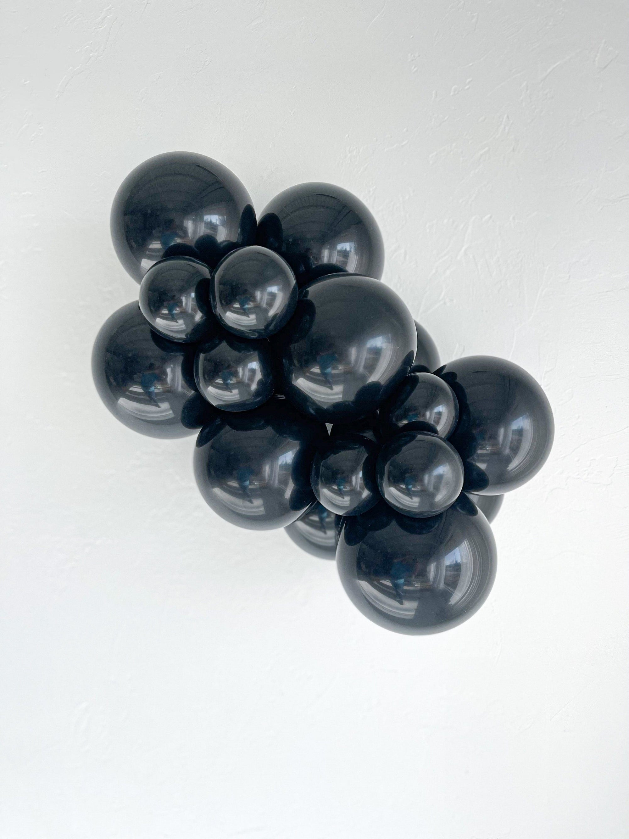 Cluster of black tuftex balloons on a white background