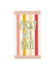 A paper napkin shaped like a beach towel with a multicoloured striped background and the text 'VACAY ALL DAY!' in gold foil lettering, fringed edges.