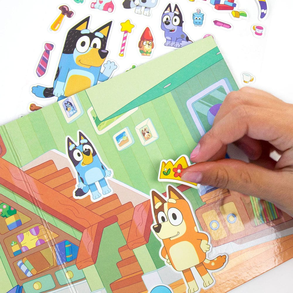 Hand placing crown sticker on Bluey indoor house play scene with Bandit and Bingo puffy stickers; repositionable Bluey activity set ages 3+
