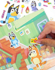 Hand placing crown sticker on Bluey indoor house play scene with Bandit and Bingo puffy stickers; repositionable Bluey activity set ages 3+