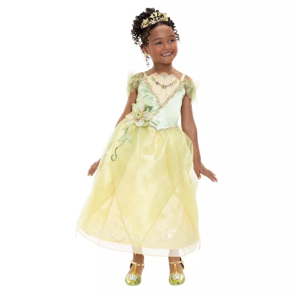 Girl wearing Disney Princess Tiana costume dress with gold tiara and shoes; green and yellow Signature Collection dress for ages 3+ sizes 3T–10