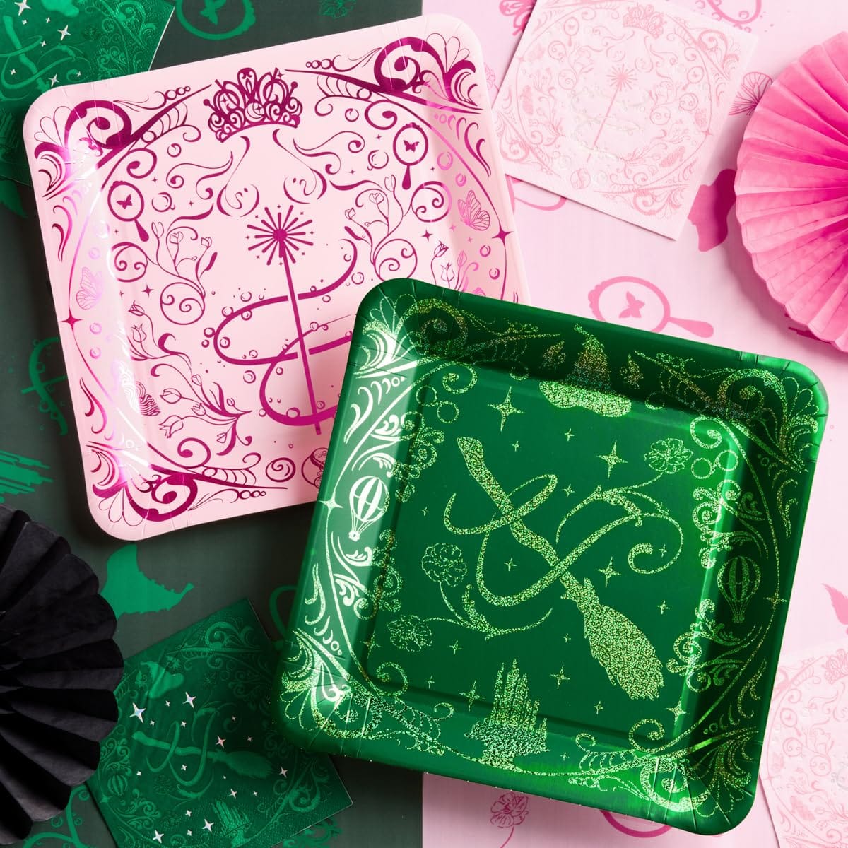 Wicked party table with pink and green Emerald City plates, matching napkins, and paper fans