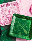 Wicked party table with pink and green Emerald City plates, matching napkins, and paper fans