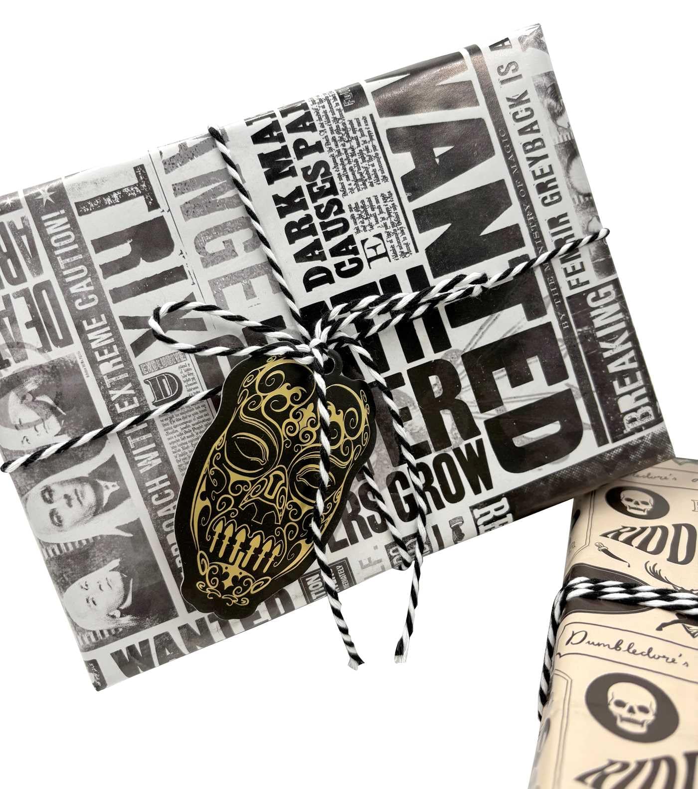 Harry Potter Dark Arts Gift Wrap Set with Daily Prophet newspaper-style wrapping paper featuring Bellatrix Lestrange Wanted posters and dark magic headlines, tied with black and white baker's twine and finished with a gold and black Death Eater mask die-cut gift tag; perfect for Harry Potter themed party gifts, birthdays, and Wizarding World celebrations