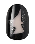 Close-up of Kiss x Wicked For Good black press-on nail with Elphaba witch hat silhouette and silver glitter; glow-in-the-dark fake nails; wicked party favours