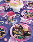 K-Pop Demon Hunters party supplies styled table setting with plates cups napkins and cupcakes in pink and purple theme