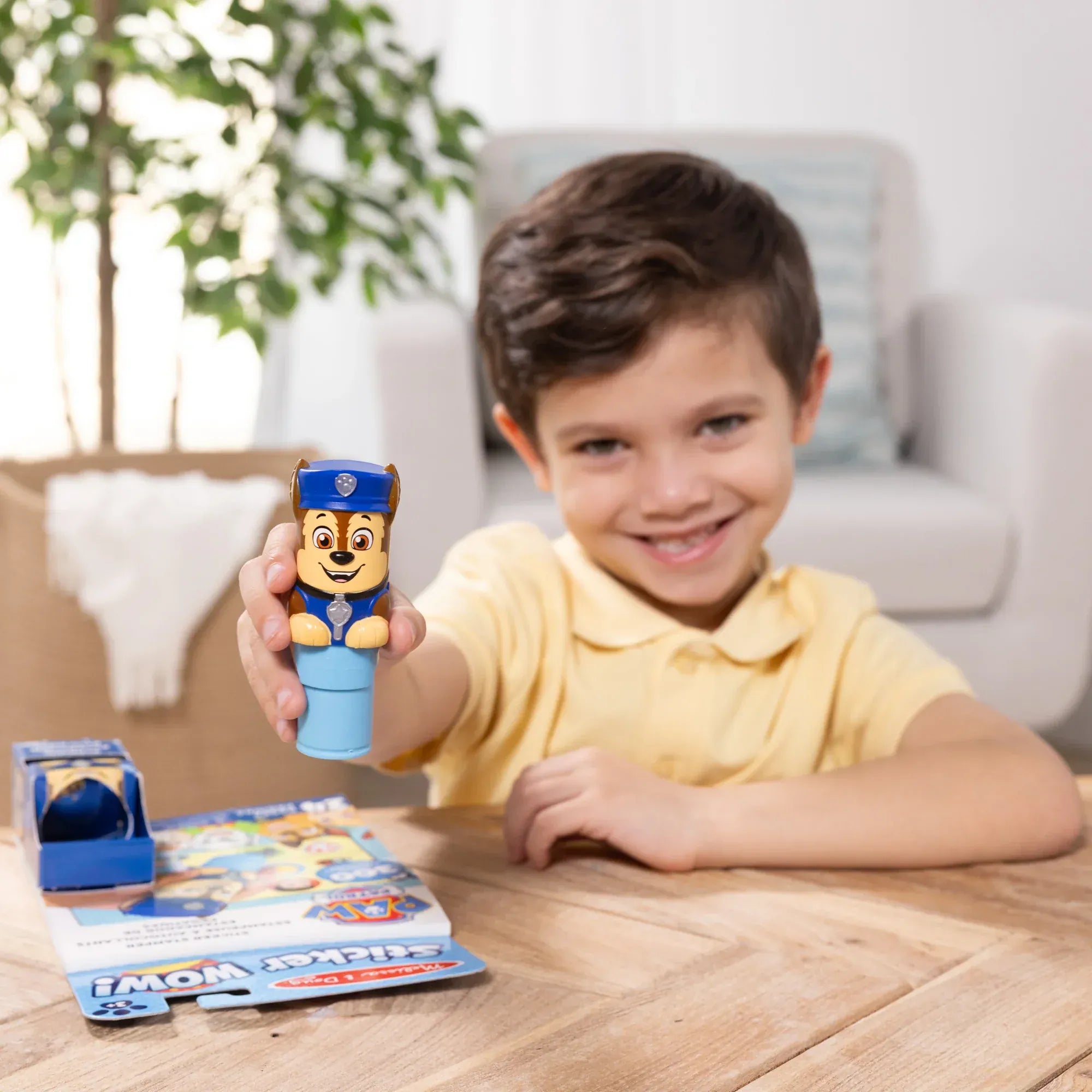 Happy child displaying PAW Patrol Chase sticker stamper collectible toy with activity pages, perfect birthday party gift and entertainment for preschoolers
