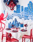 Elegant Spider-Man themed party table setup with NYC city skyline backdrop white balloons themed cake and complete party supplies and decorations for kids birthday