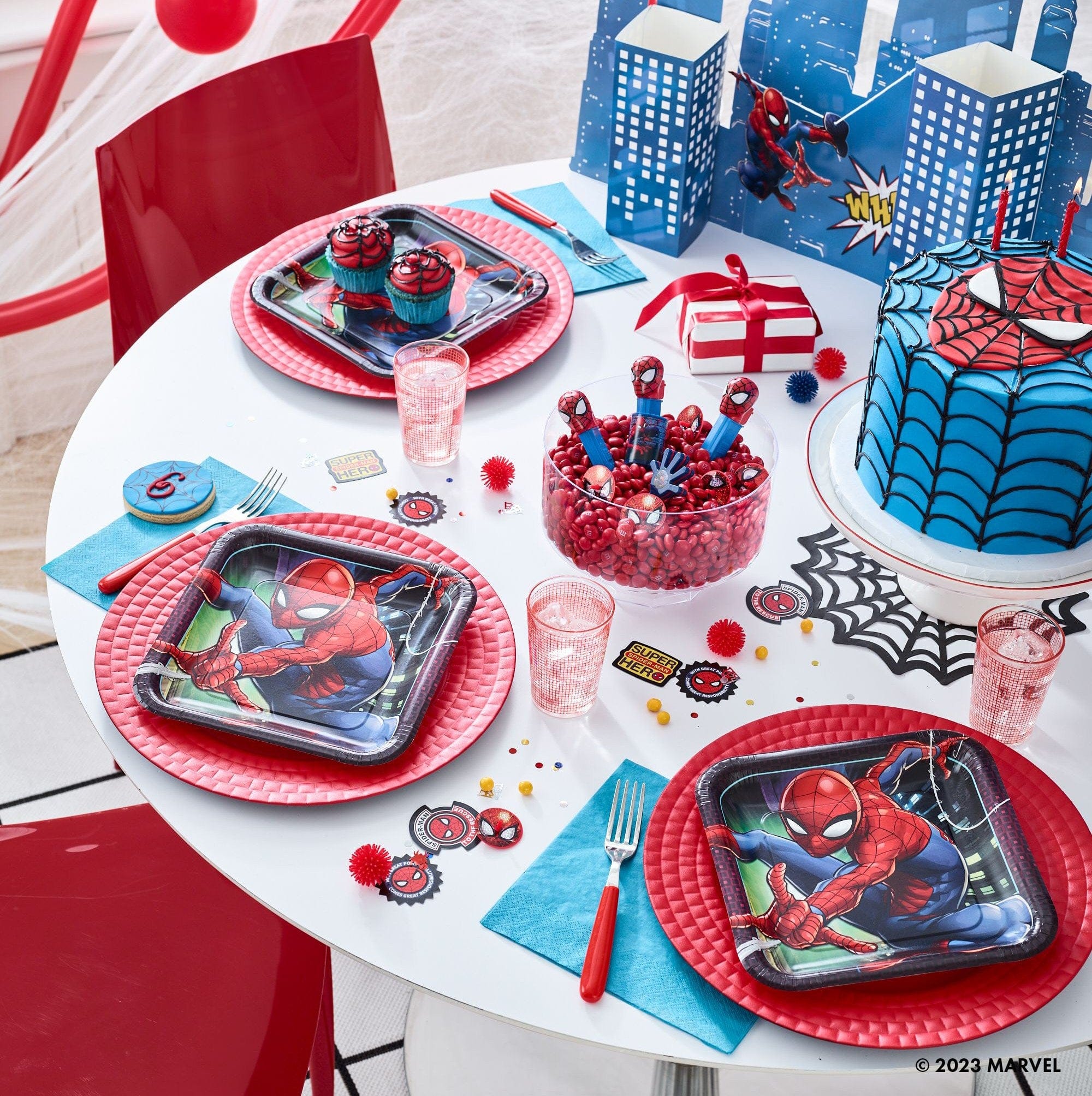 Children's Spider-Man themed birthday party table setting with themed napkins , 9 inch square lunch  plates, cups, and cake.  Decorated with coordinated spiderman themed party tableware for kids birthday