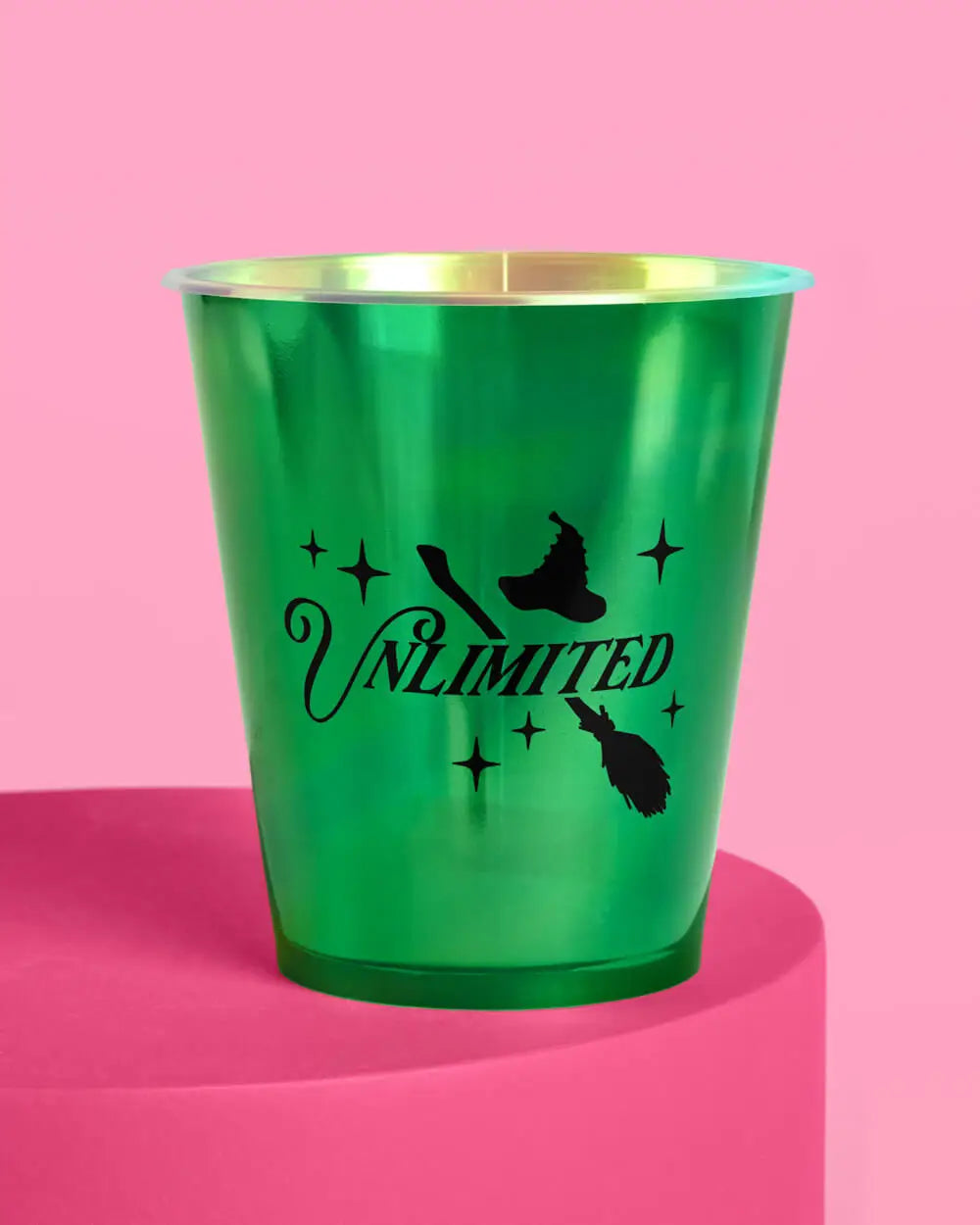 Wicked Unlimited green metallic party cup closeup showing witch hat broom and sparkle design on pink background