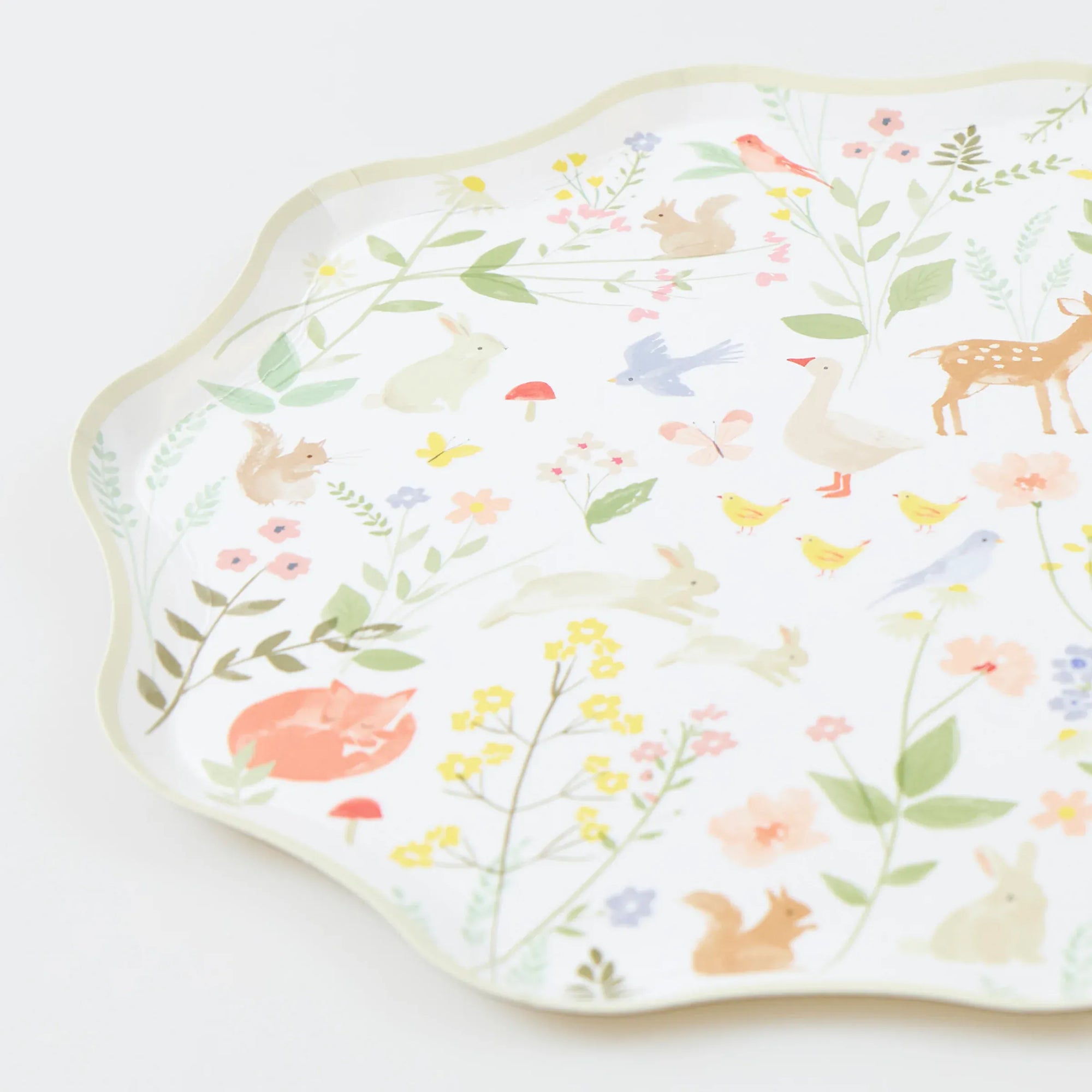 Close up of cream Meri Meri Little Animals cake plate with waved edge, watercolour bunnies, fox and wildflowers